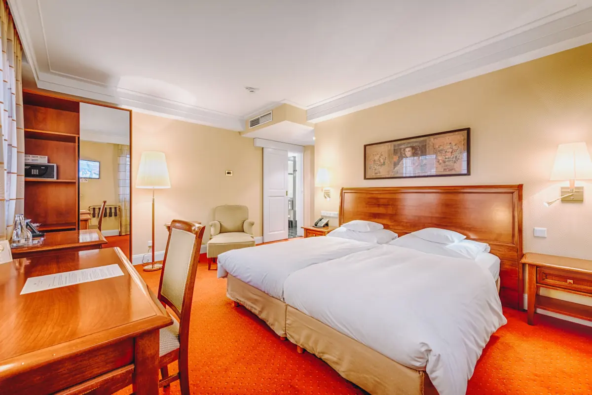 Hotelzimmer mit warmem Holzmobiliar und rotem Teppich