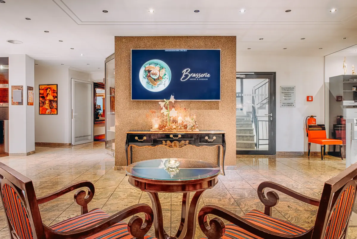 Lobby mit Kamin und Sesseln vor dem Eingang zur Brasserie