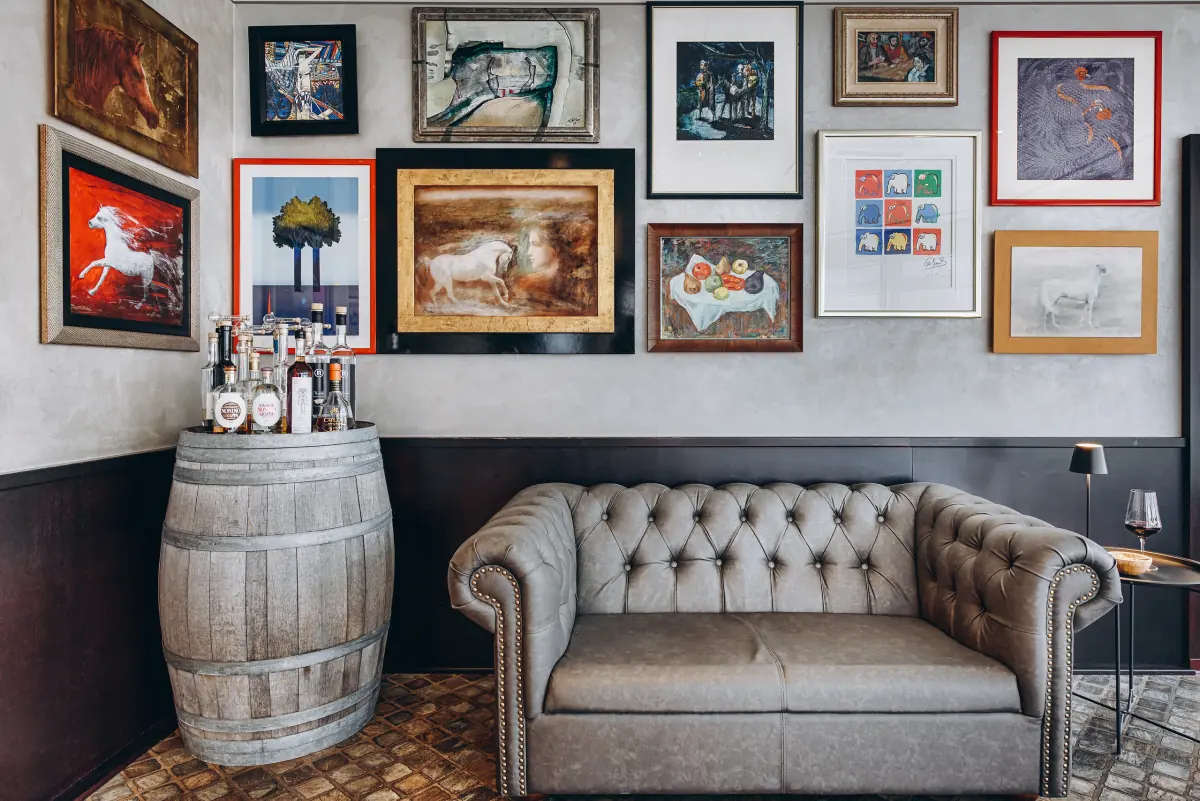 Chesterfield-Sofa und Weinfass vor einer Wand voller Bilder