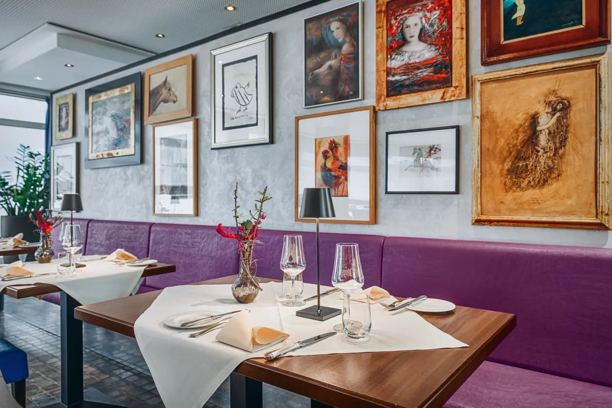 Gedeckter Tisch vor violetter Bank und Kunstwand