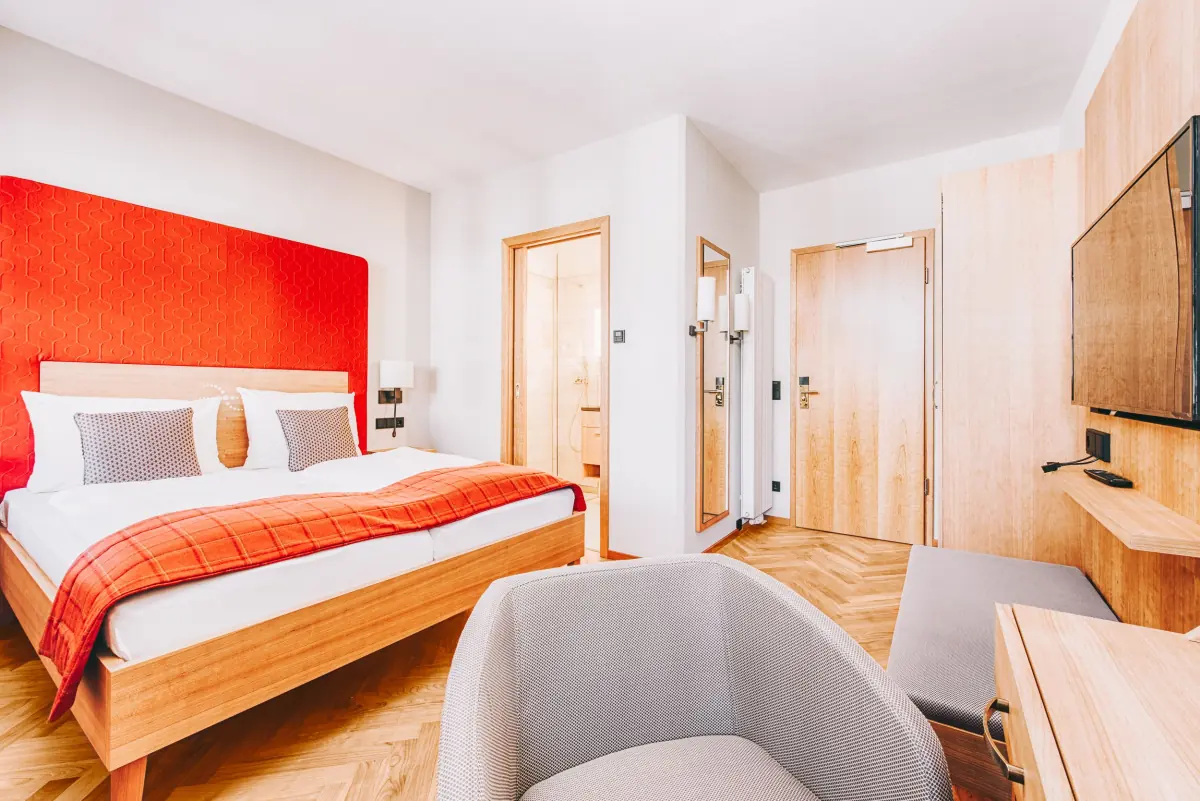 Hotelzimmer mit rotem Kopfteil und Holzmöbeln