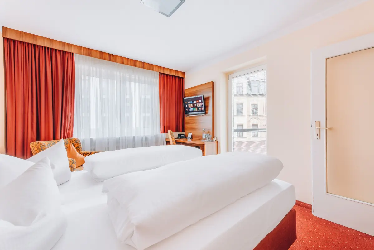 Helles Zimmer mit roten Vorhängen und großen Fenstern