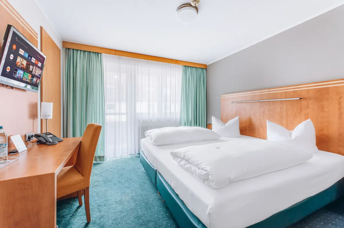 Zimmer mit Holzmöbeln und mintgrünen Vorhängen