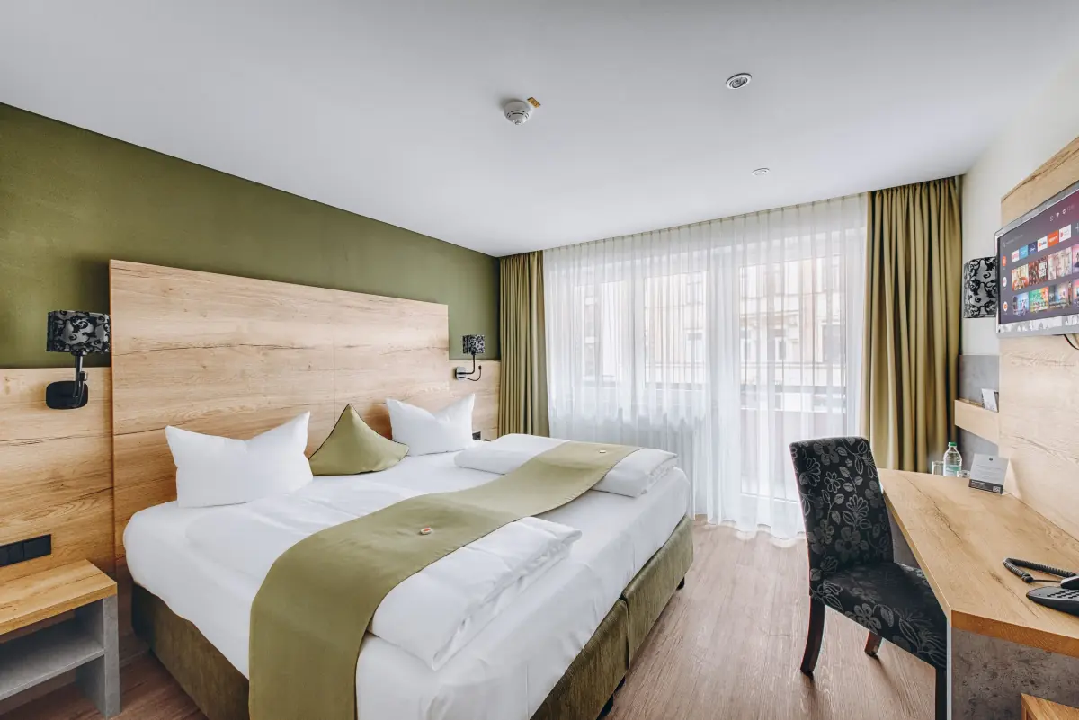 Doppelzimmer mit olivgrünen Akzenten und Holzkopfteil
