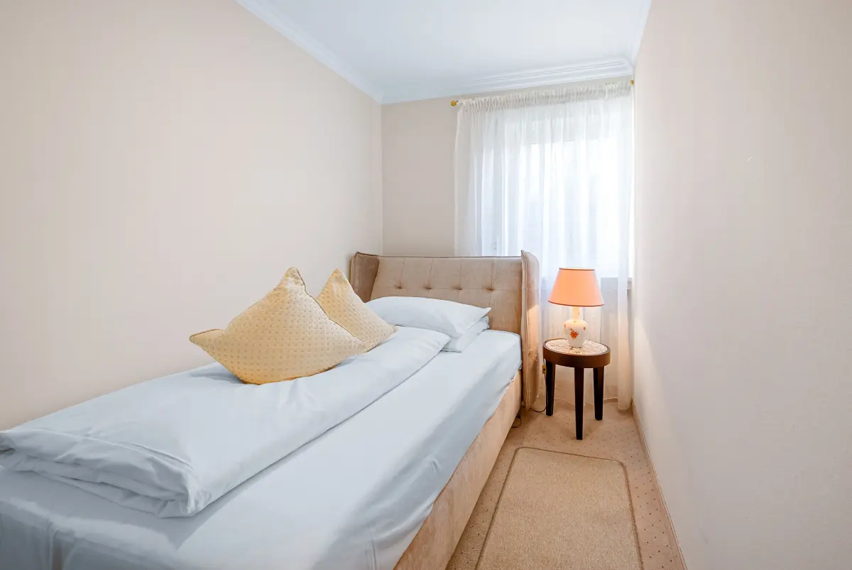Einzelzimmer mit Sessel und Tischlampe