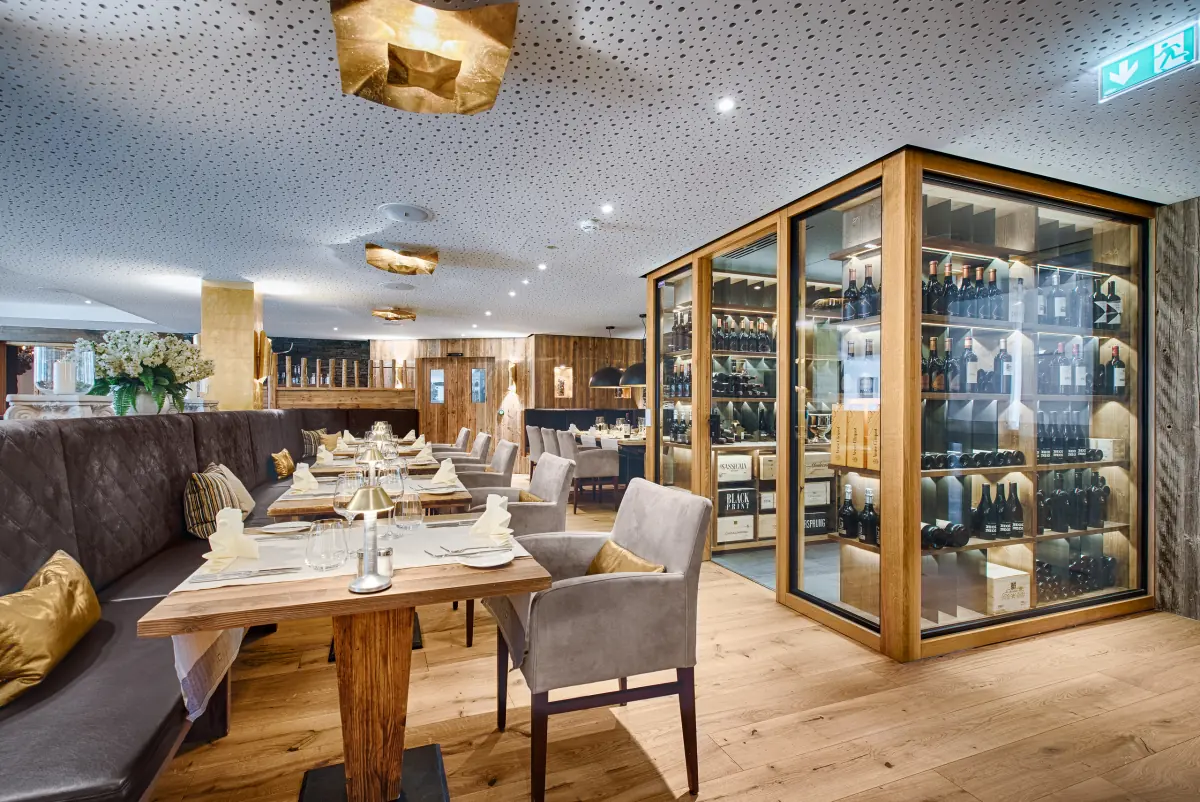 Restaurantecke mit beleuchtetem Weinschrank und Holztischen