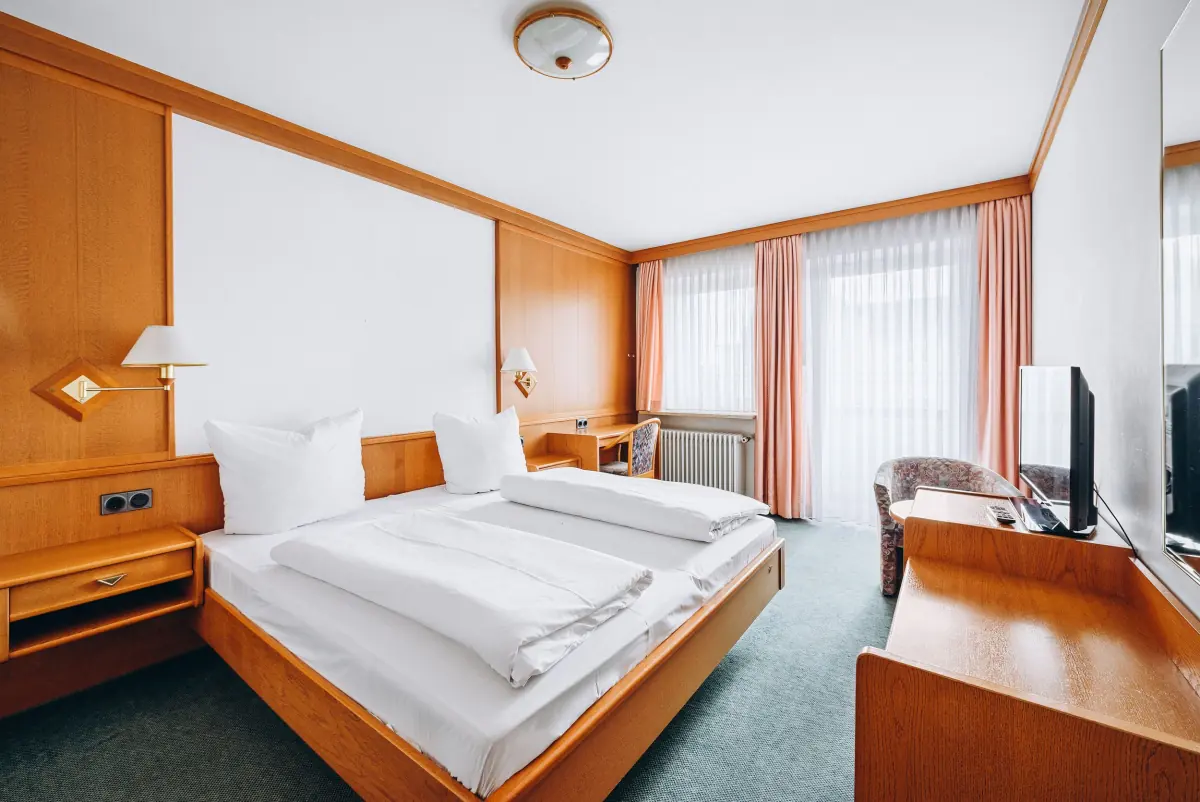 Helles Zimmer mit Holzmöbeln und großen Fenstern