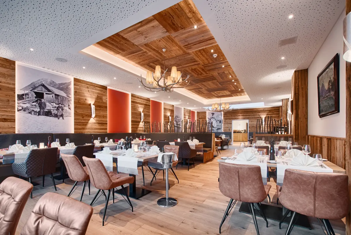Restaurant mit Holzdecke, Kronleuchtern und gedeckten Tischen