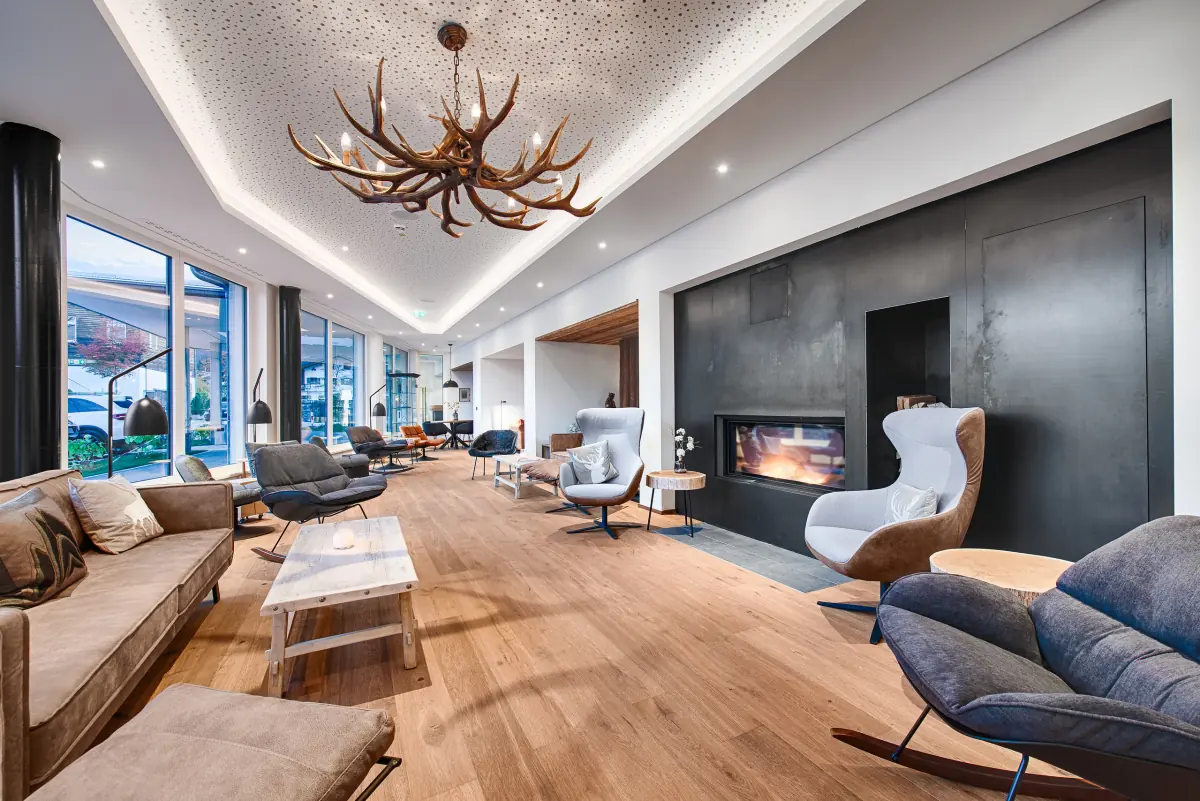 Lobby mit Kamin, Geweihleuchter und Sesseln