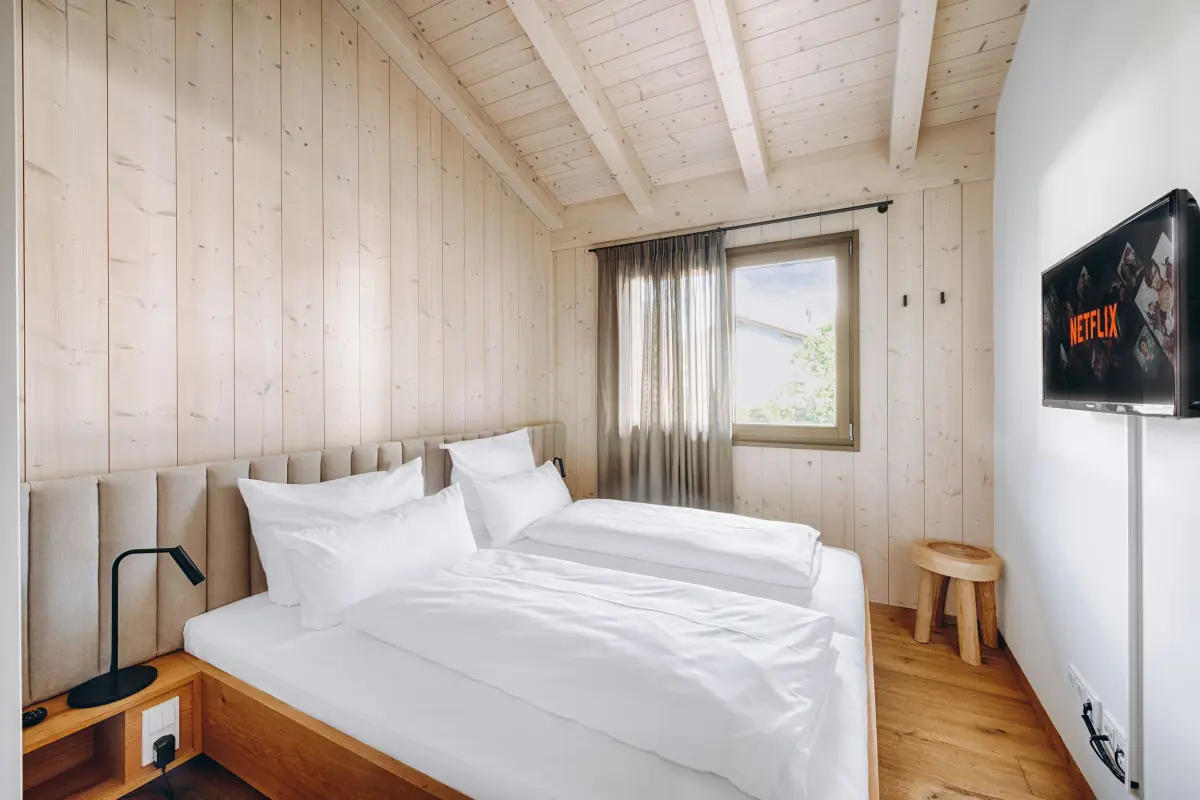 Zimmer mit Holzbalken und weißer Bettwäsche
