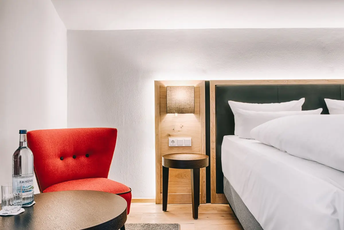 Zimmer mit rotem Sessel und weißem Bett